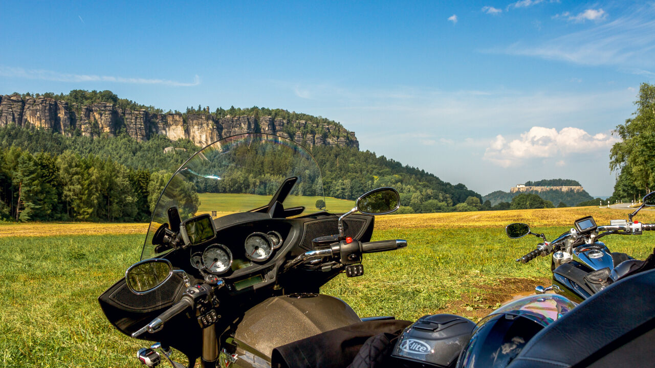 Lenker eines Tourenmotorrads im Vordergrund, dahinter ein langgestreckter Tafelberg mit Felswänden